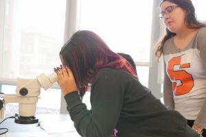 Female HS student looking through microscope.