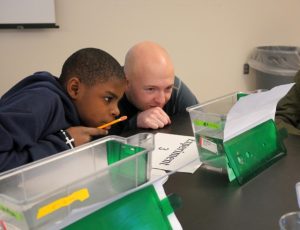 Teacher and one male HS student observing a Zebrafish.